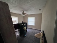 an empty bedroom with a fan and a bed