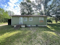 a small green house in the middle of a grassy yard