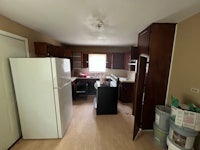 an empty kitchen with wood floors and a refrigerator