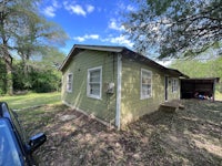 a small green house with a car parked in front of it