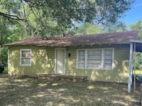 a small house in the woods with a green roof