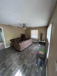 an empty living room with hardwood floors and a ceiling fan