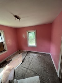 an empty room with pink walls and a window