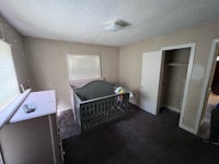an empty room with a crib and dresser